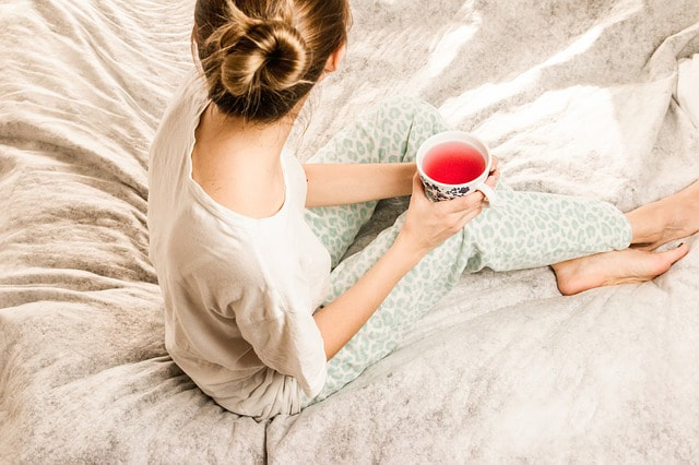 girl on bed holding a mug comfortable after ant control